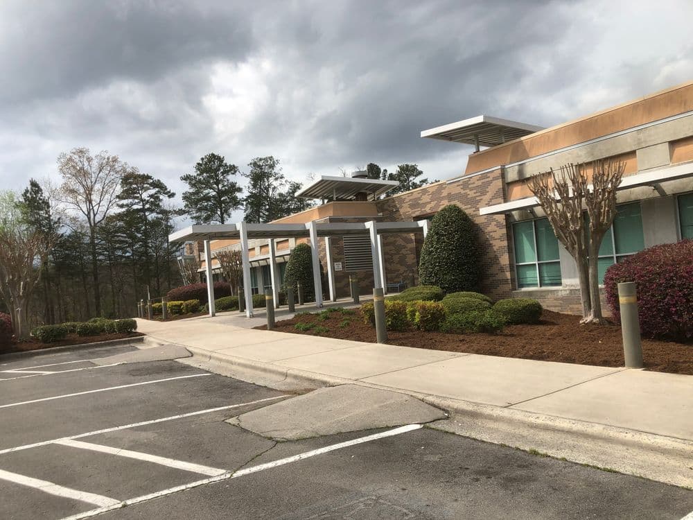 Modern commercial building exterior with landscaped parking lot and cloudy sky.