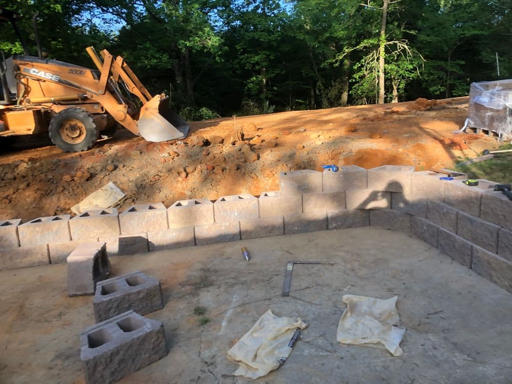Excavator at a construction site with concrete blocks arranged for building foundation.